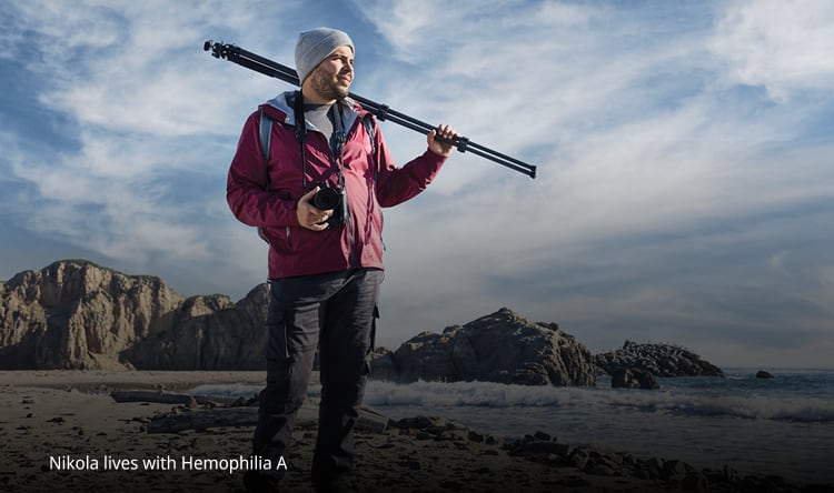 person standing on a beach, holding camera equipment and looking into the distance